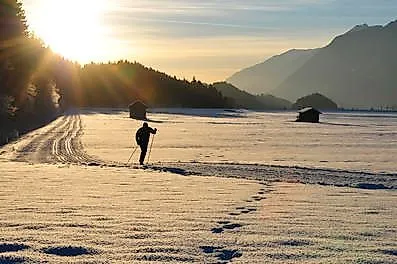 Langläufer bei Sonnenaufgang in verschneiter Winterlandschaft in Kramsach