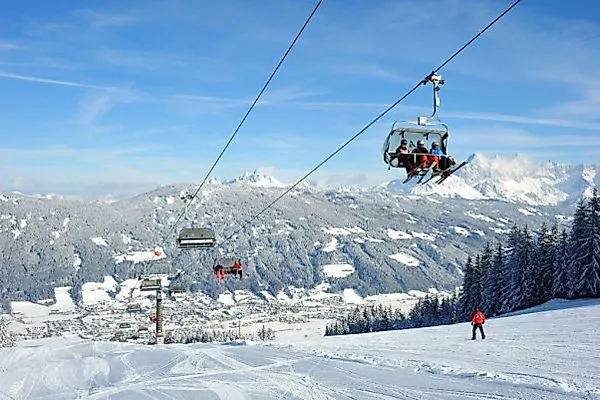Skifahrer und Sessellift auf verschneiter Skipiste in Radstadt mit Alpenpanorama.