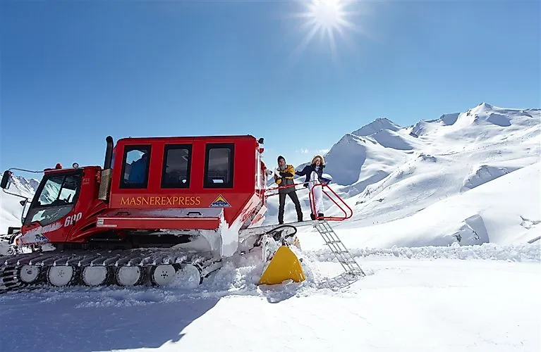 Winterabenteuer in Serfaus mit dem roten Masner-Express vor schneebedeckter Bergkulisse.