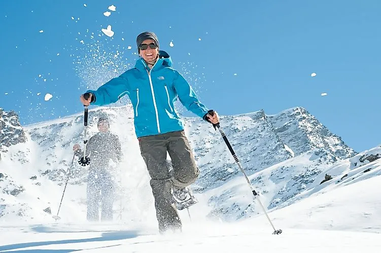 Zwei Personen beim Schneeschuhwandern vor schneebedecktem Bergpanorama in Corvatsch