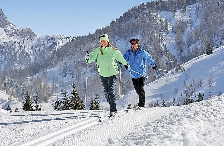 Zwei Langläufer genießen sonniges Winterwetter auf der Loipe bei Windischgarsten.