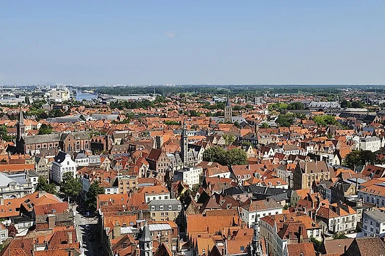 Luftaufnahme des Stadtteils Zeebrugge mit dicht gedrängten roten Ziegeldächern und Kirchtürmen unter klarem, blauem Himmel.