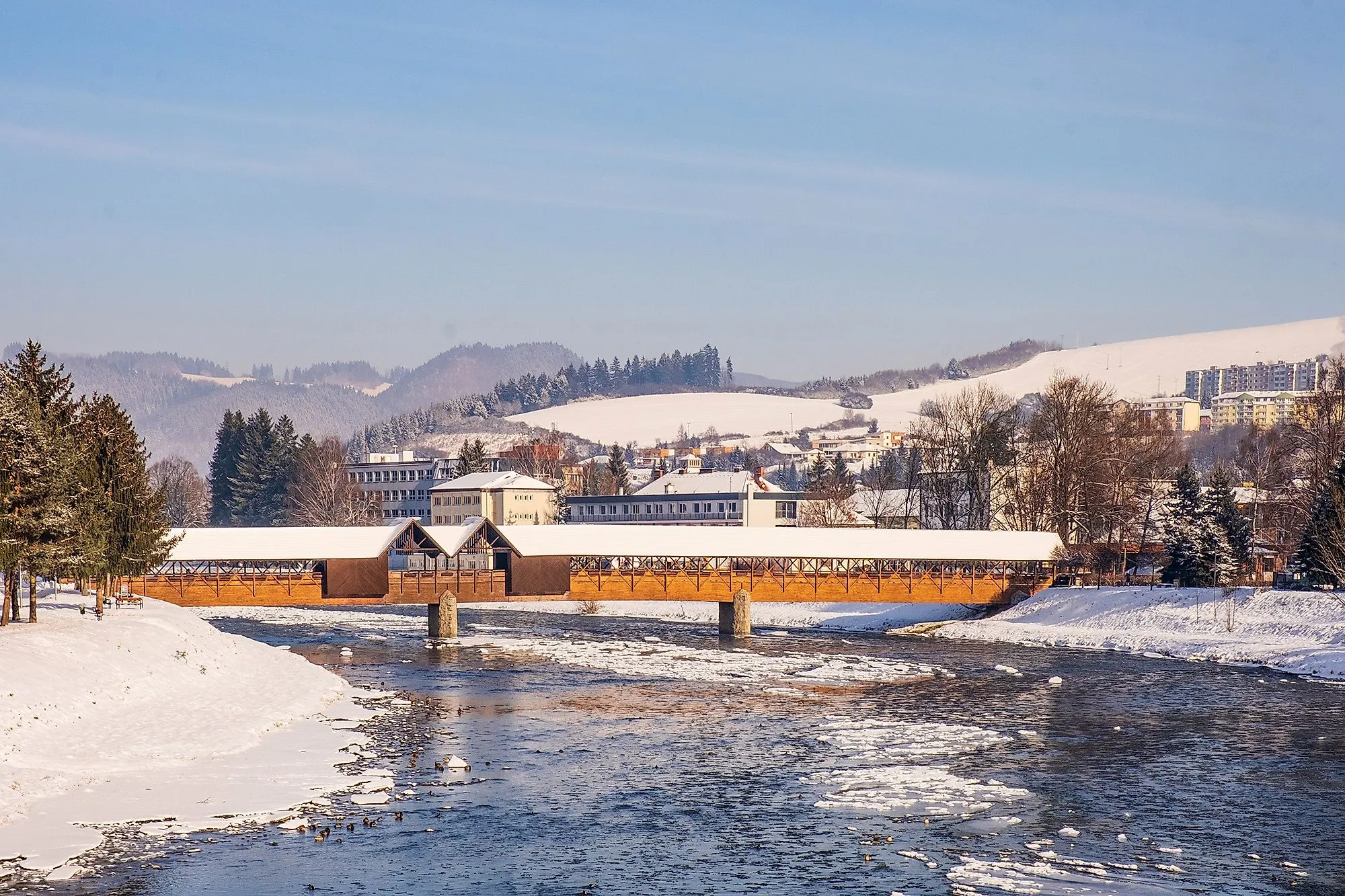 Winter in Dolny Kubin mit überdachter Holzbrücke und verschneiten Hügeln