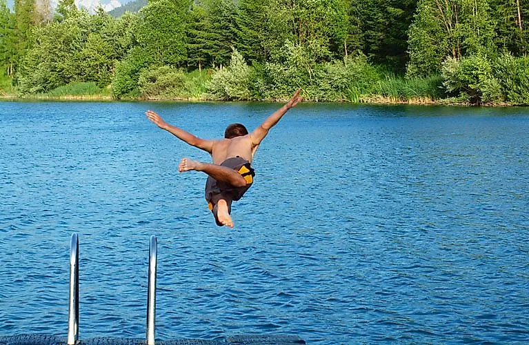 Junge springt in einen klaren See in Kärnten beim Sommerurlaub