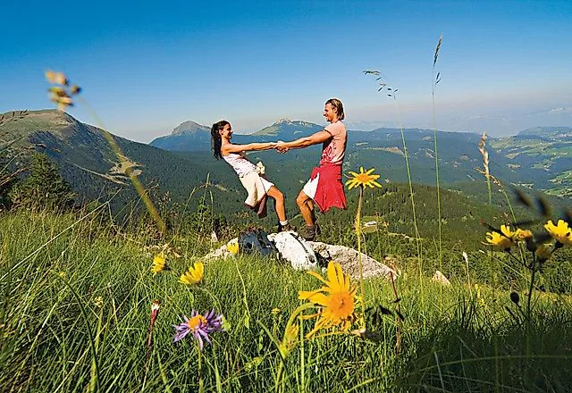 Koppel geniet van een wandelvakantie op een alpenweide met uitzicht op de bergen in Obereggen, Zuid-Tirol
