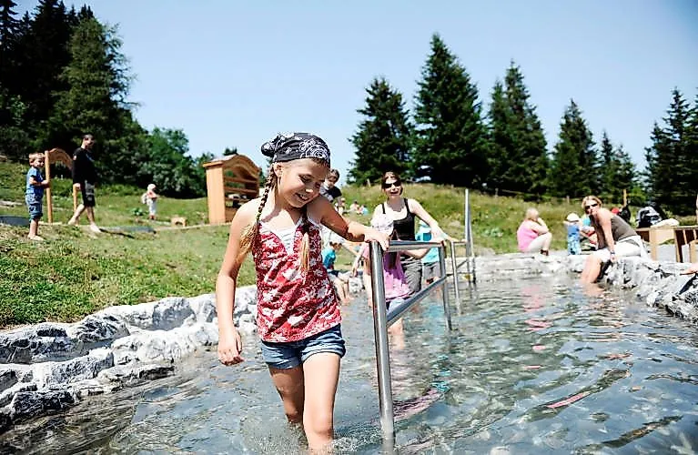 Mädchen läuft lachend durch ein Wasserbecken am Berg in Wangs-Pizol