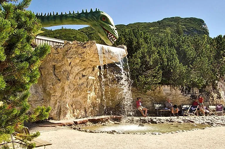 Wasserspielplatz mit Dinofigur im Triassic Park Waidring auf der Steinplatte