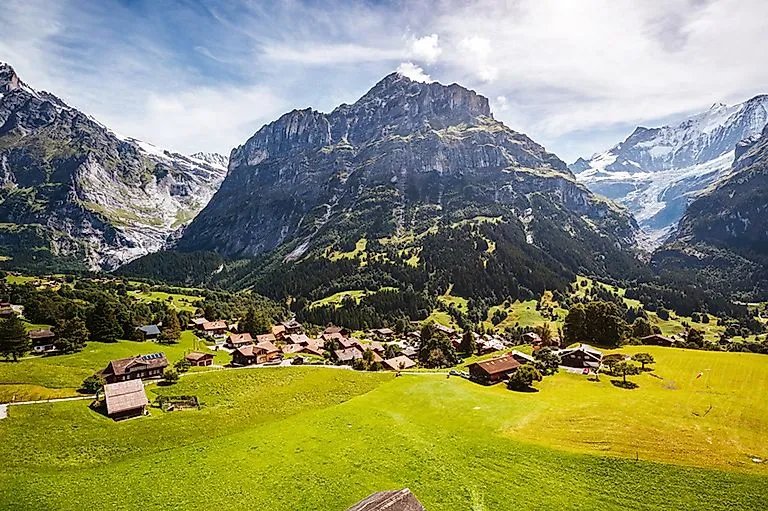 Blick auf das idyllische Dorf Grindelwald mit traditionellen Chalets, eingebettet in die grüne Berglandschaft des Berner Oberlands in der Schweiz.