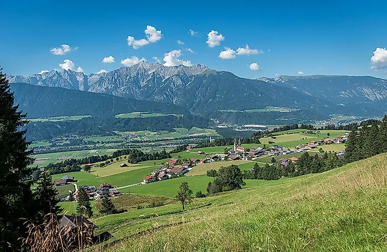 Weitläufige Sommerlandschaft mit Dorf Weerberg und Bergpanorama im Hintergrund.