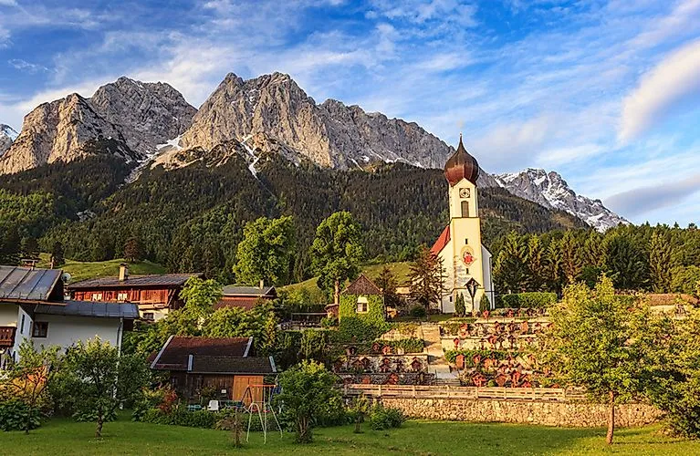 View of Grainau with church in front of the Zugspitze on a sunny summer day in the Bavarian Alps.
