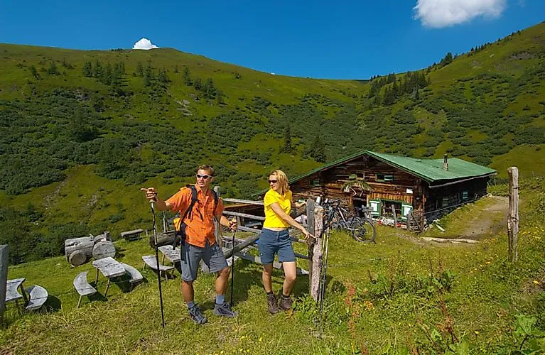 Zwei Wanderer vor einer Almhütte inmitten grüner Wiesen und Berge bei Bad Hofgastein.