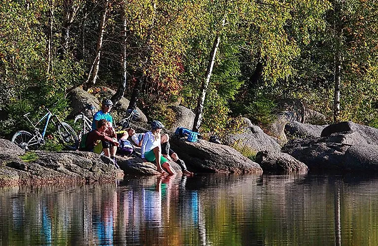 Cyklisti oddychujú na brehu jazera v lese za slnečného počasia v pohorí Fichtelgebirge.