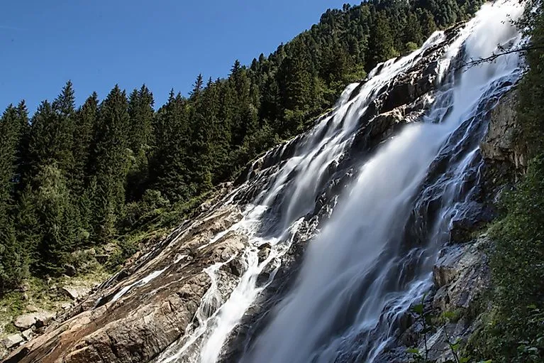 Grawa Wasserfall im Stubaital, umgeben von dichtem Nadelwald an einem sonnigen Sommertag in Tirol.