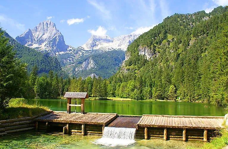 Bergsee mit Holzsteg in der Pyhrn-Priel-Region, umgeben von Bergen und Wäldern in Oberösterreich