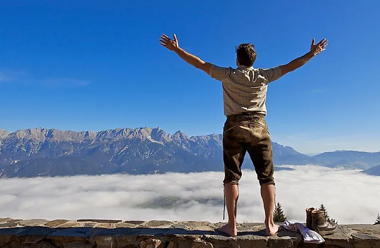 Barfußwanderer genießt die Aussicht auf die Salzburger Bergwelt über einem Nebelmeer bei Saalfelden Leogang.