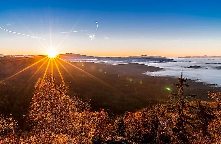 Sonnenaufgang über den herbstlich gefärbten Wäldern bei Bodenmais im Bayerischen Wald mit weitem Blick über das Nebelmeer.